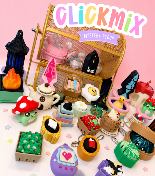 A Clickmix Mystery Scoop collection of small, colorful novelty items, including miniature cakes, a mushroom character, a duck, and a purple heart-shaped charm, arranged around a gold metal storage basket on a pink background.