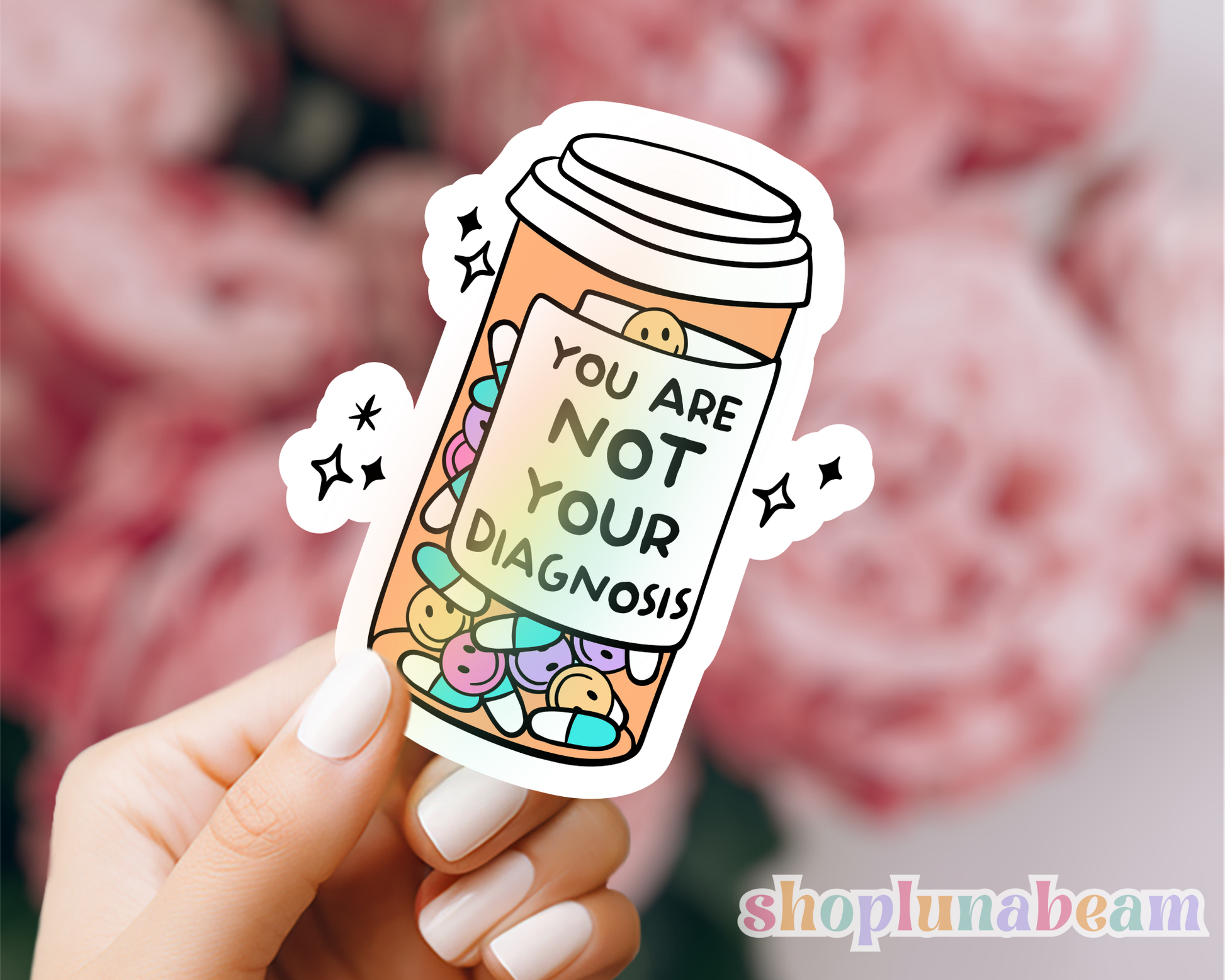 Sticker with pill bottle design and text 'You are not your diagnosis' held by a hand.