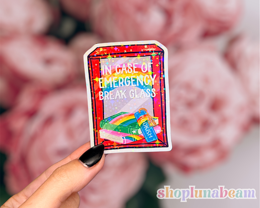 Colorful card with 'In case of emergency, break glass' text held by a hand against a blurred background.